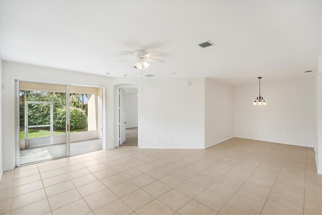 tiled empty room featuring ceiling fan with notable chandelier