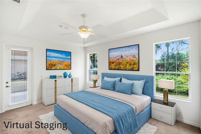 carpeted bedroom with a tray ceiling, access to outside, multiple windows, and ceiling fan