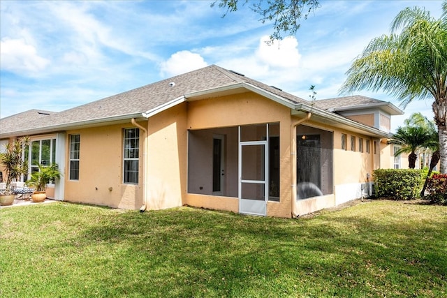 rear view of house with a lawn and a sunroom