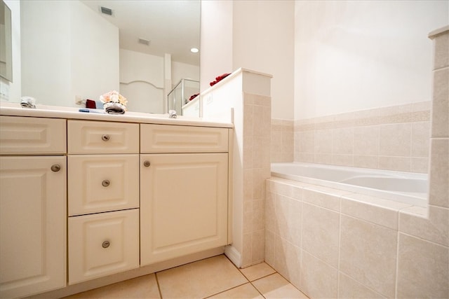 bathroom with tile patterned flooring, vanity, and a relaxing tiled tub