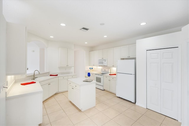 kitchen featuring light tile patterned flooring, kitchen peninsula, white appliances, a kitchen island, and white cabinets