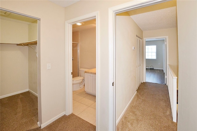 corridor featuring light colored carpet and a textured ceiling