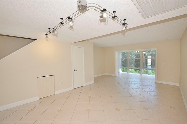 spare room featuring a textured ceiling and light tile patterned floors