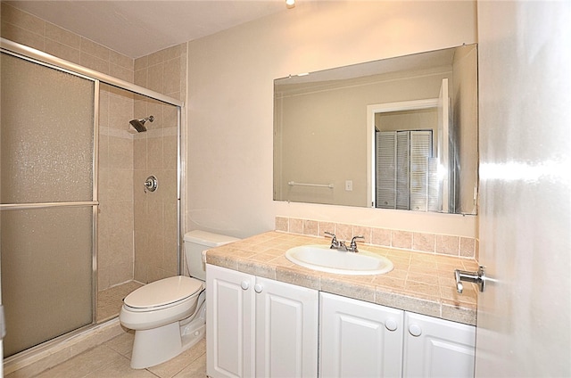 bathroom featuring toilet, vanity, an enclosed shower, and tile patterned flooring