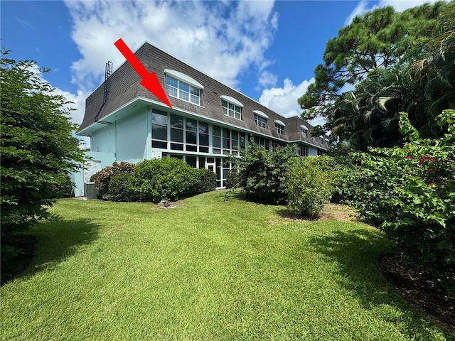 back of house featuring a lawn and a sunroom