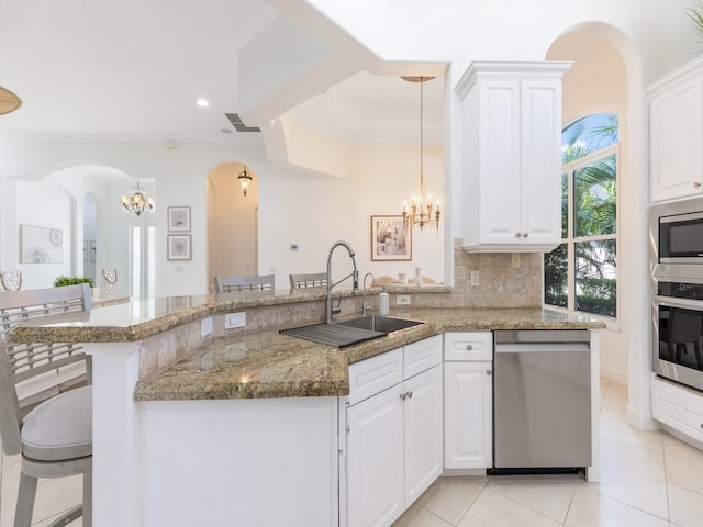 kitchen with stainless steel appliances, sink, a breakfast bar, white cabinets, and pendant lighting