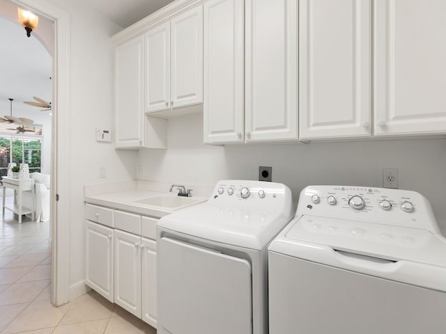 laundry room featuring cabinets, light tile patterned flooring, sink, ceiling fan, and washing machine and dryer