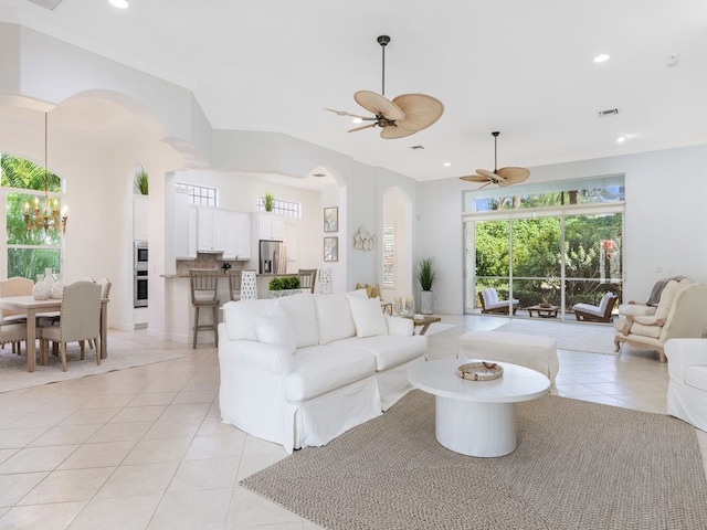 living room with ceiling fan with notable chandelier, light tile patterned floors, and crown molding