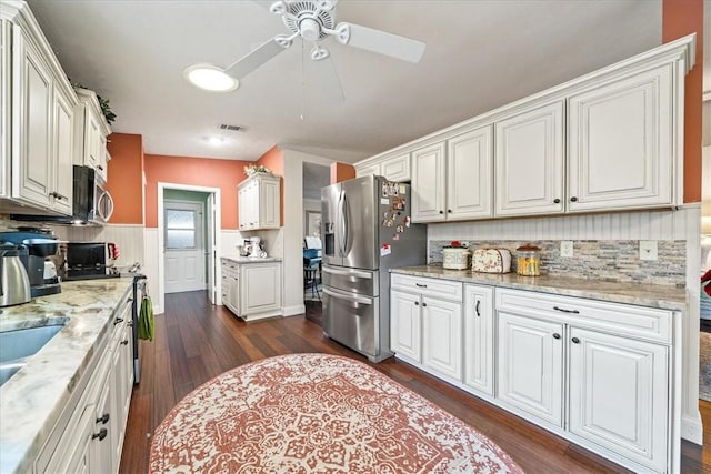 kitchen with dark wood-style floors, visible vents, light stone countertops, stainless steel appliances, and white cabinetry