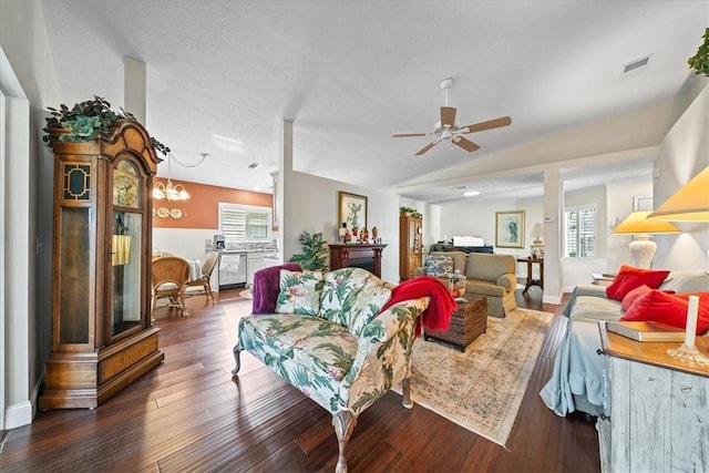 living area with visible vents, ceiling fan with notable chandelier, wood finished floors, baseboards, and lofted ceiling