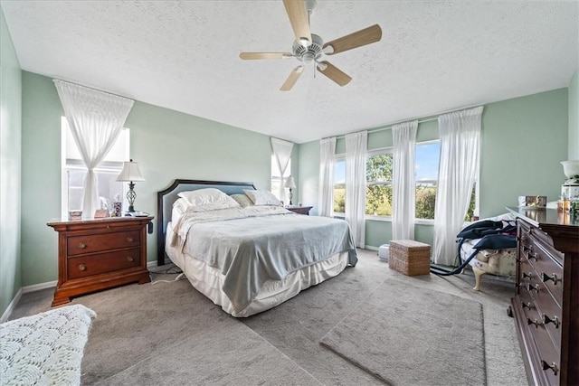 carpeted bedroom featuring baseboards, a textured ceiling, and a ceiling fan