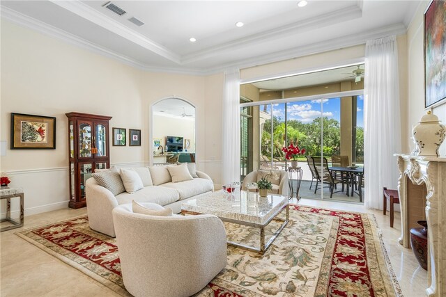 tiled living room featuring ornamental molding, a tray ceiling, and ceiling fan