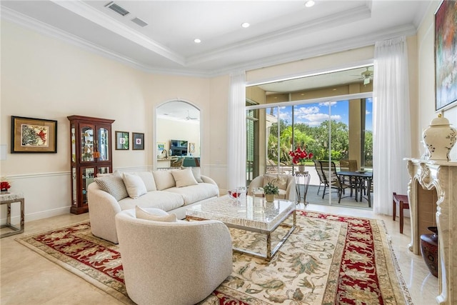 living area with a tray ceiling, crown molding, arched walkways, a ceiling fan, and recessed lighting