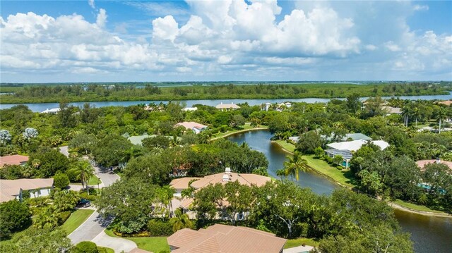 aerial perspective of suburban area with a nearby body of water and a tree filled landscape