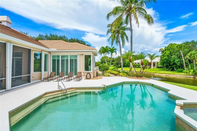 view of swimming pool with a patio, a pool with connected hot tub, and a water view