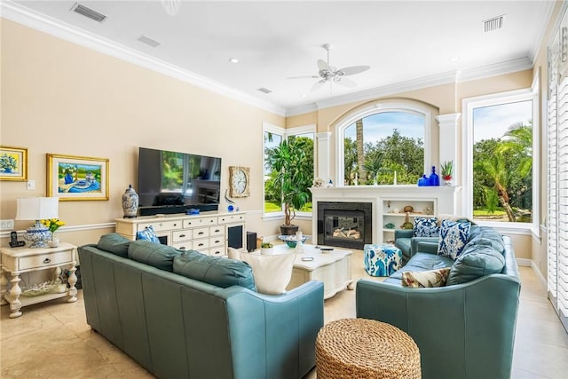 living room with ceiling fan, a glass covered fireplace, ornamental molding, recessed lighting, and light tile patterned flooring