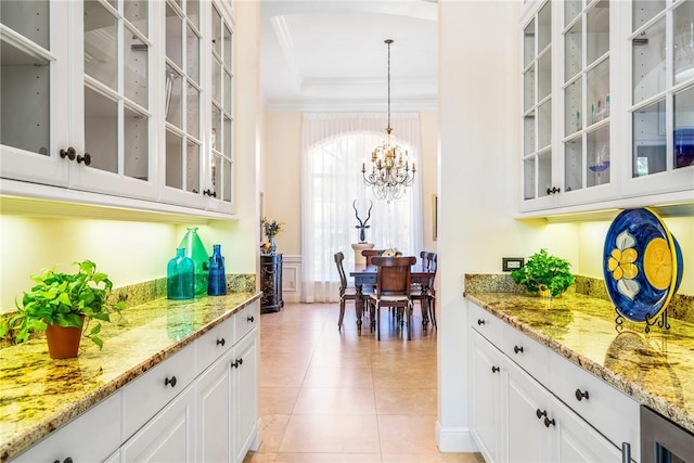 bar with crown molding, a chandelier, light tile patterned flooring, a raised ceiling, and pendant lighting