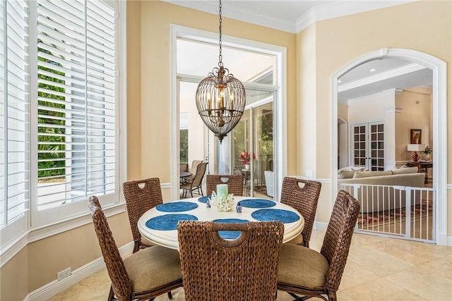 dining room with a chandelier, crown molding, arched walkways, tile patterned flooring, and baseboards