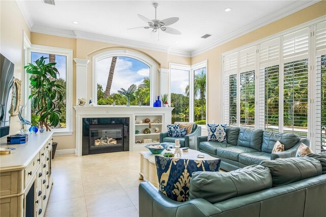 living area featuring ceiling fan, light tile patterned flooring, a tile fireplace, ornamental molding, and recessed lighting