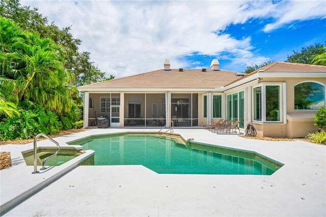 view of swimming pool with a sunroom, a patio, and a pool with connected hot tub