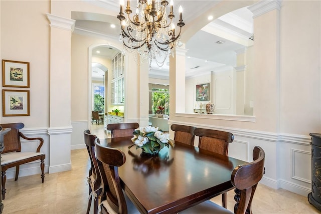 dining space with arched walkways, ornamental molding, a decorative wall, a chandelier, and a wainscoted wall