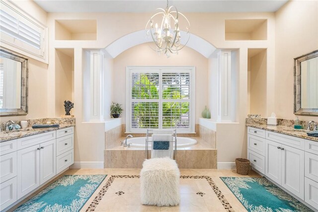full bathroom with a garden tub, tile patterned floors, two vanities, a chandelier, and baseboards