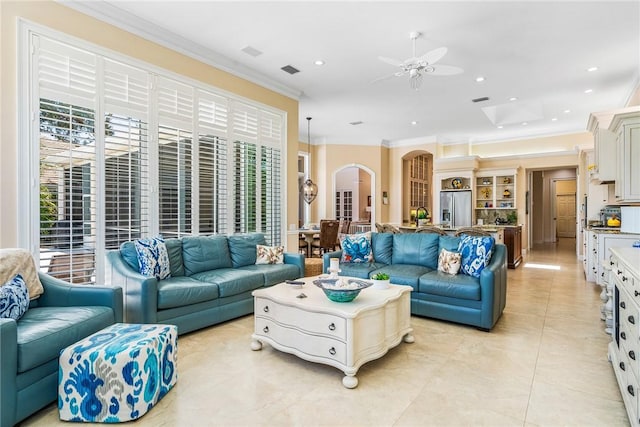 living area with arched walkways, ornamental molding, healthy amount of natural light, ceiling fan, and light tile patterned floors