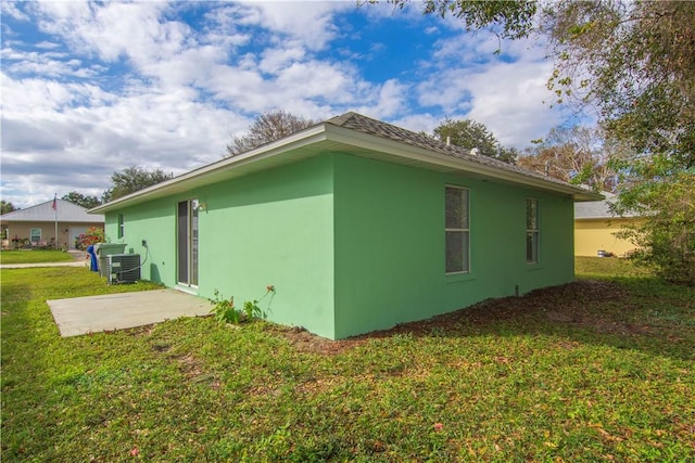 view of side of home with a yard, central AC unit, and a patio area