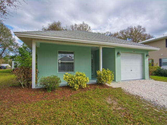 single story home with a garage, covered porch, and a front yard