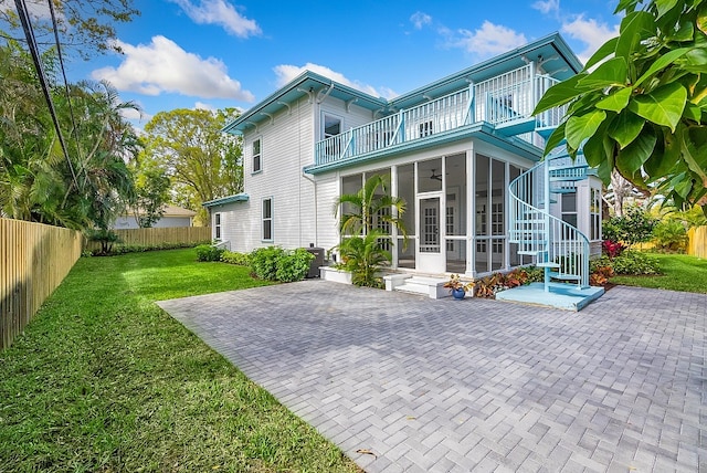 rear view of house featuring a sunroom, a patio area, a balcony, and a yard