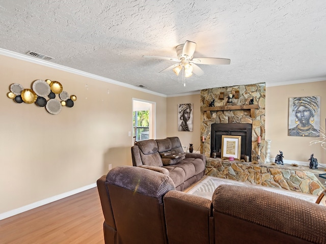 living room with ornamental molding, ceiling fan, a textured ceiling, a fireplace, and wood-type flooring