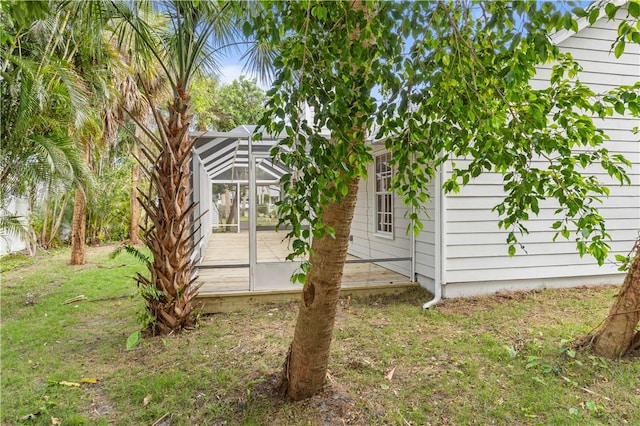 rear view of property featuring a yard and glass enclosure