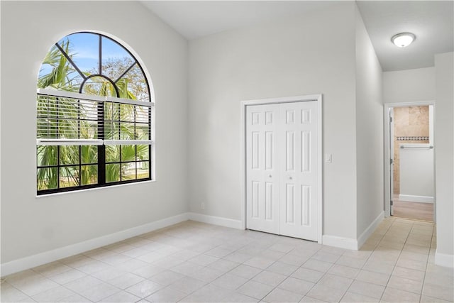 unfurnished bedroom with a closet, light tile patterned floors, and multiple windows