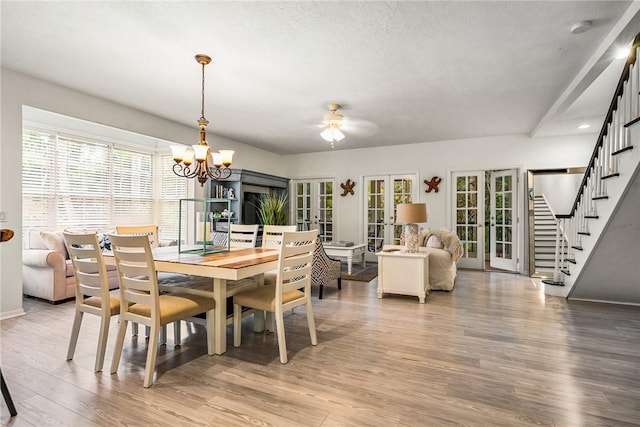 dining space with stairway, light wood-style flooring, plenty of natural light, and ceiling fan with notable chandelier