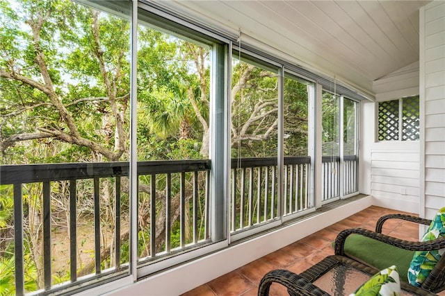 sunroom with tile patterned floors and vaulted ceiling
