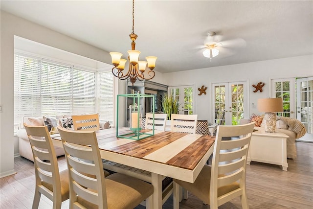 dining space with light wood-style floors, french doors, plenty of natural light, and ceiling fan with notable chandelier