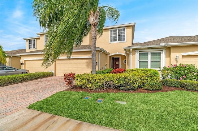 view of front of home featuring a garage, a front yard, decorative driveway, and stucco siding