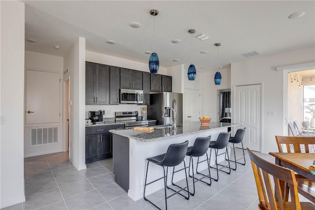 kitchen featuring visible vents, light tile patterned floors, a breakfast bar, and stainless steel appliances
