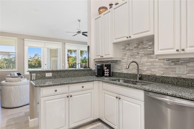 kitchen with dark stone counters, white cabinets, sink, stainless steel dishwasher, and kitchen peninsula