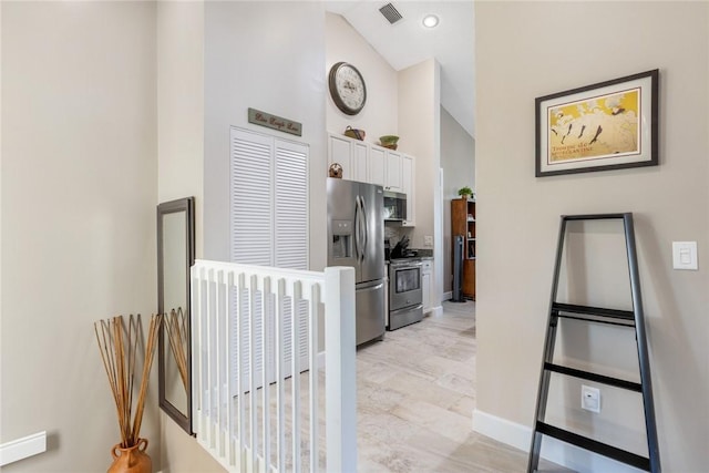 kitchen featuring white cabinetry, stainless steel appliances, and high vaulted ceiling