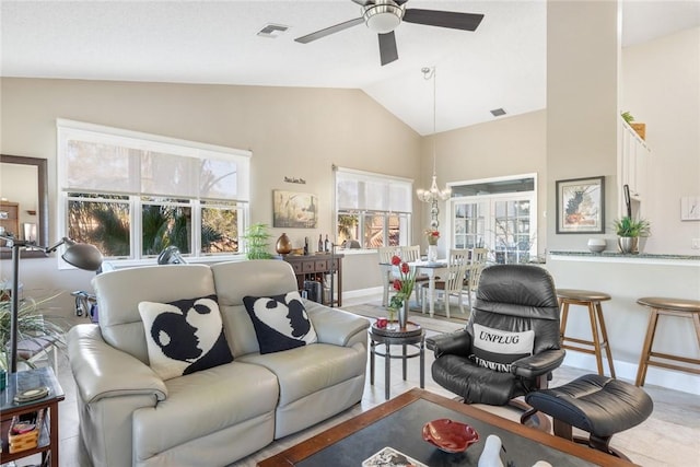 living room featuring ceiling fan with notable chandelier, vaulted ceiling, and plenty of natural light