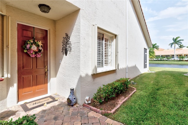 view of exterior entry featuring a lawn