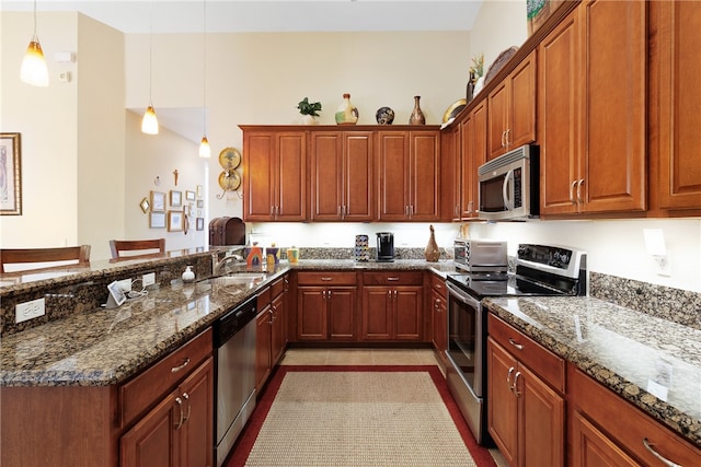 kitchen featuring stainless steel appliances, hanging light fixtures, dark stone counters, and sink