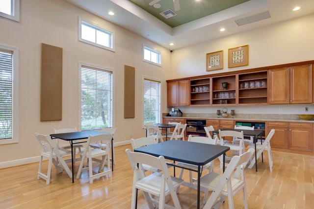 dining room featuring a high ceiling, light hardwood / wood-style flooring, and a wealth of natural light