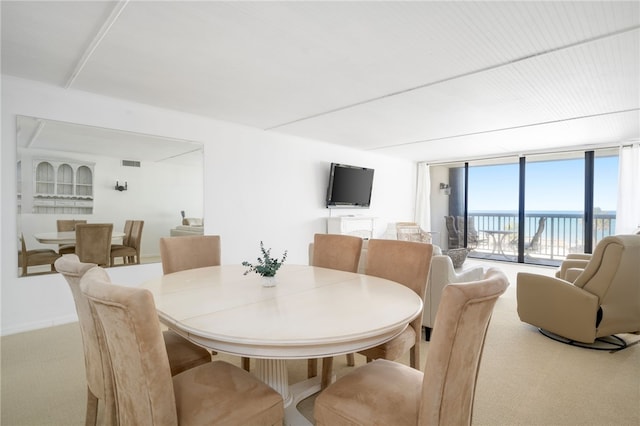 carpeted dining room featuring a wall of windows