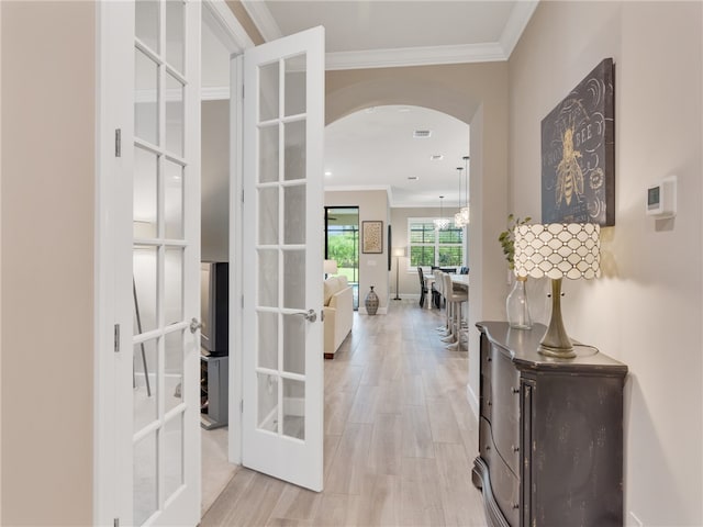 corridor featuring french doors, light hardwood / wood-style floors, and crown molding