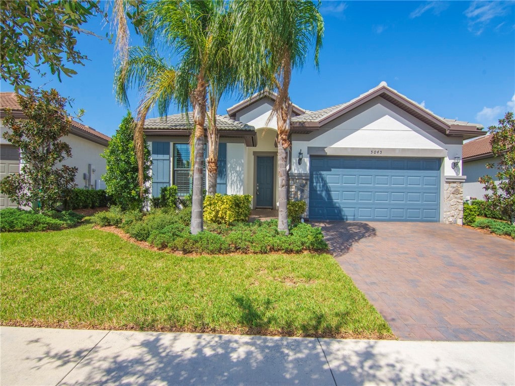 ranch-style house featuring a garage and a front lawn