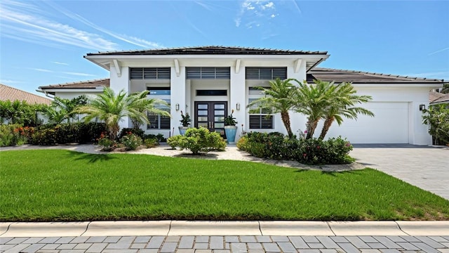 9378 Orchid Cove Cir, Vero Beach, FL 32963 - view of front of property with a front yard, a garage, decorative driveway, stucco siding, and french doors