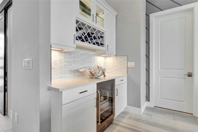 9378 Orchid Cove Cir, Vero Beach, FL 32963 - bar featuring decorative backsplash, beverage cooler, a bar, baseboards, and light wood-type flooring