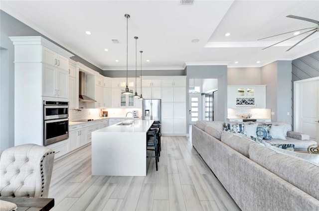 9378 Orchid Cove Cir, Vero Beach, FL 32963 - kitchen with decorative backsplash, a kitchen breakfast bar, wall chimney range hood, appliances with stainless steel finishes, and open floor plan